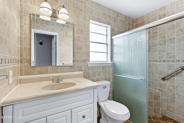 bathroom with vanity, toilet, an enclosed shower, and tile walls