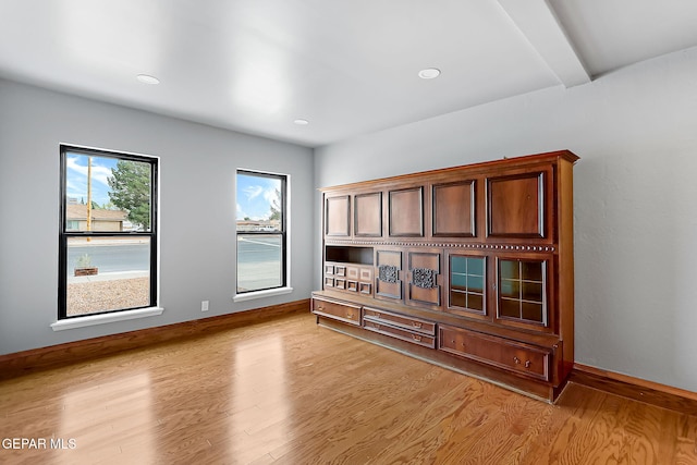 unfurnished room featuring beam ceiling and light hardwood / wood-style flooring