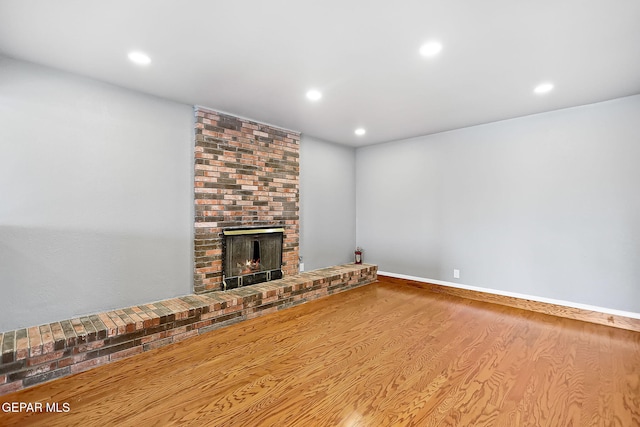 unfurnished living room with a brick fireplace and hardwood / wood-style flooring