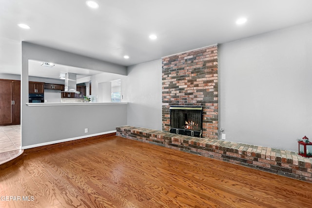 unfurnished living room with a fireplace and light wood-type flooring