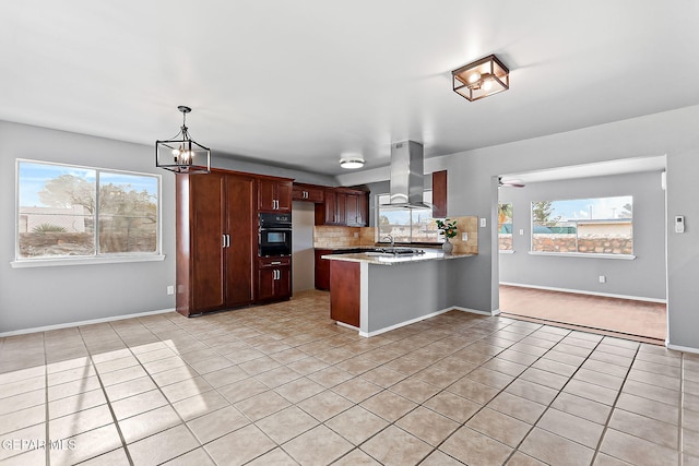 kitchen with wall chimney exhaust hood, plenty of natural light, oven, and kitchen peninsula