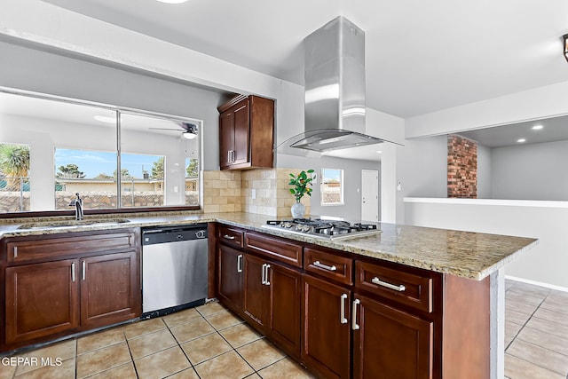 kitchen featuring kitchen peninsula, light stone countertops, stainless steel appliances, sink, and wall chimney range hood