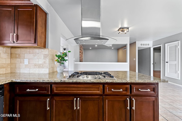 kitchen with kitchen peninsula, island range hood, light stone counters, and stainless steel gas stovetop