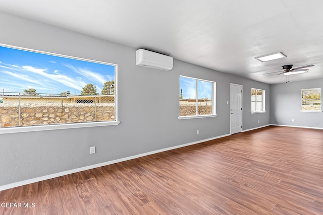 empty room featuring an AC wall unit, ceiling fan, and hardwood / wood-style floors