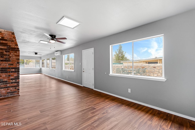 unfurnished living room featuring a wall mounted AC, ceiling fan, and wood-type flooring