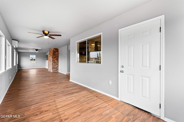 interior space featuring hardwood / wood-style flooring, ceiling fan, and a wall mounted air conditioner