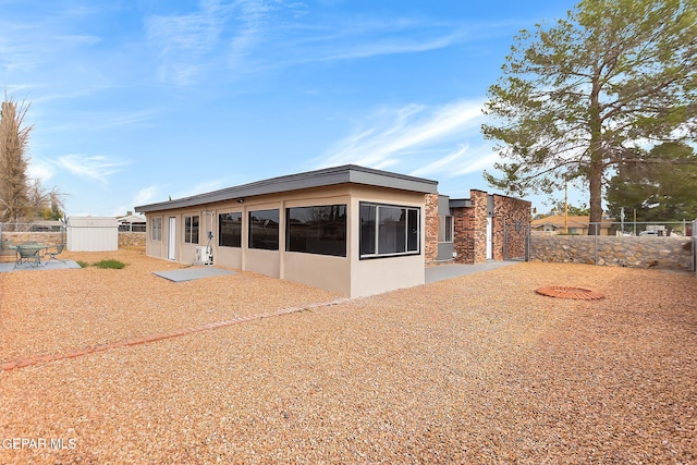 back of property with a patio and a shed