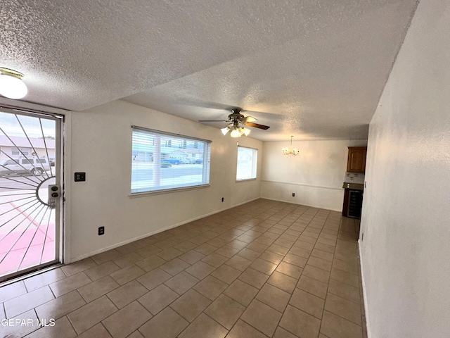 unfurnished living room featuring tile patterned flooring, ceiling fan with notable chandelier, and a textured ceiling