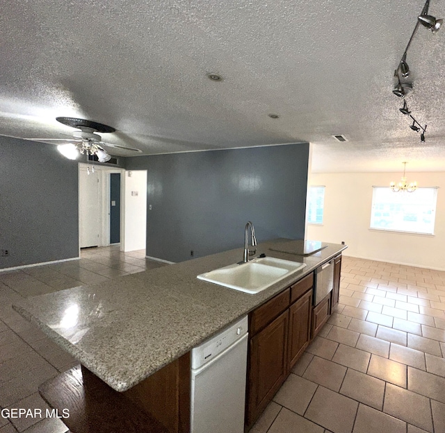 kitchen with sink, dishwasher, an island with sink, light tile patterned flooring, and ceiling fan with notable chandelier