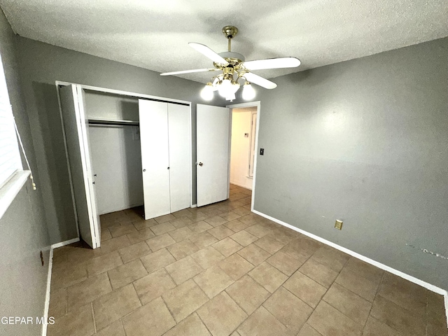 unfurnished bedroom with a textured ceiling, ceiling fan, and a closet