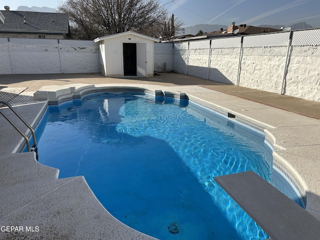 view of swimming pool featuring a diving board and a shed