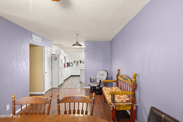 dining space with a textured ceiling and light hardwood / wood-style flooring