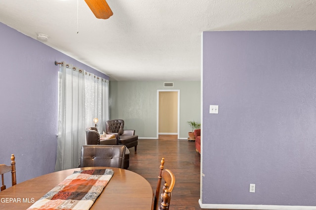 dining space with a textured ceiling, ceiling fan, and dark wood-type flooring