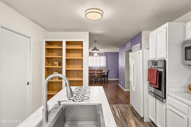 kitchen with dark hardwood / wood-style flooring, stainless steel appliances, sink, tile countertops, and white cabinets