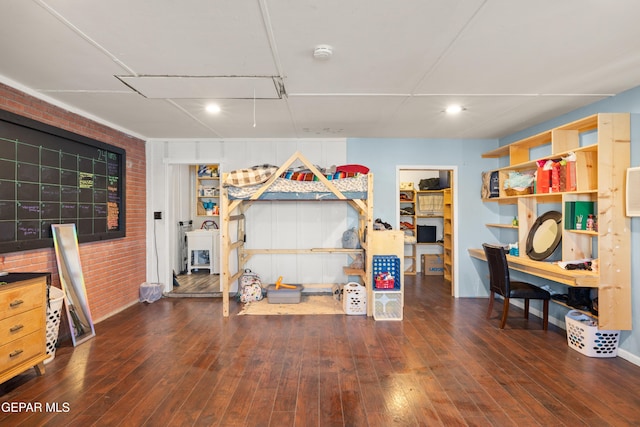 miscellaneous room featuring dark hardwood / wood-style floors and brick wall