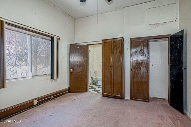 unfurnished bedroom featuring connected bathroom, light carpet, and ceiling fan