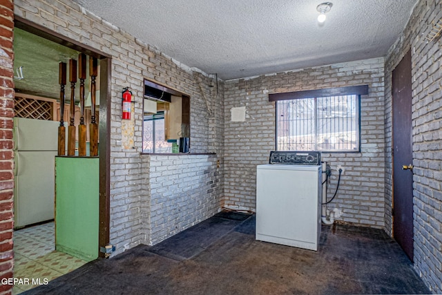 washroom with washer / dryer, a textured ceiling, and brick wall