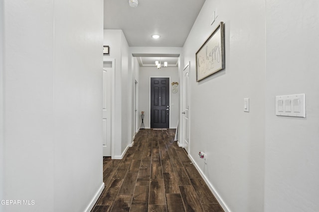 corridor with a chandelier and dark wood-type flooring