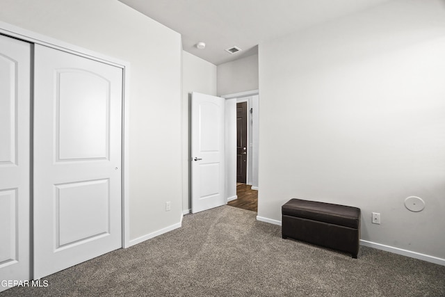 unfurnished bedroom with dark colored carpet and a closet