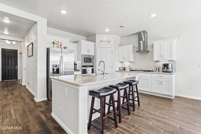 kitchen featuring white cabinets, wall chimney exhaust hood, and stainless steel appliances