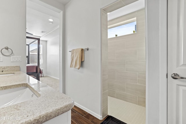 bathroom featuring hardwood / wood-style flooring, vanity, and a tile shower