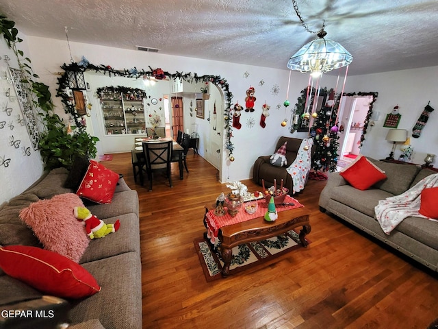 living room with a textured ceiling, hardwood / wood-style flooring, and an inviting chandelier