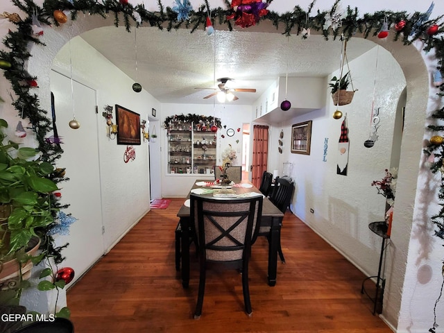 dining room with a textured ceiling, ceiling fan, and dark wood-type flooring