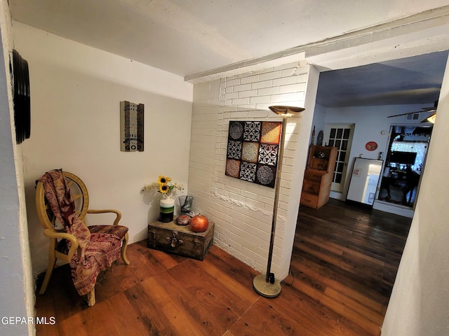 corridor featuring dark wood-type flooring and brick wall