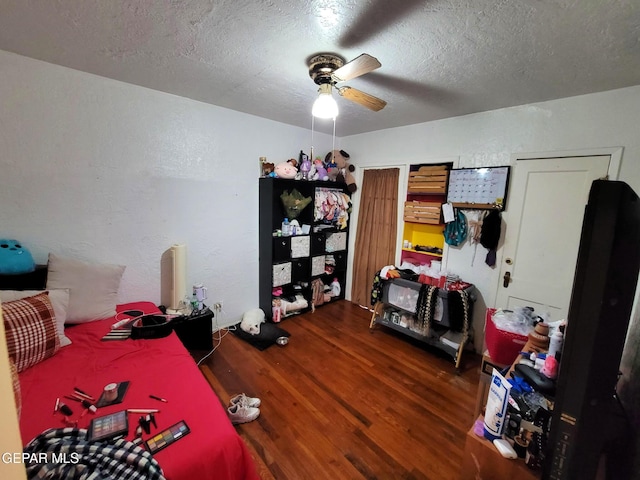 bedroom with a textured ceiling, ceiling fan, and dark wood-type flooring