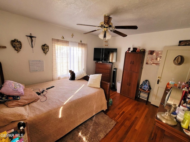 bedroom with a textured ceiling, ceiling fan, and dark wood-type flooring