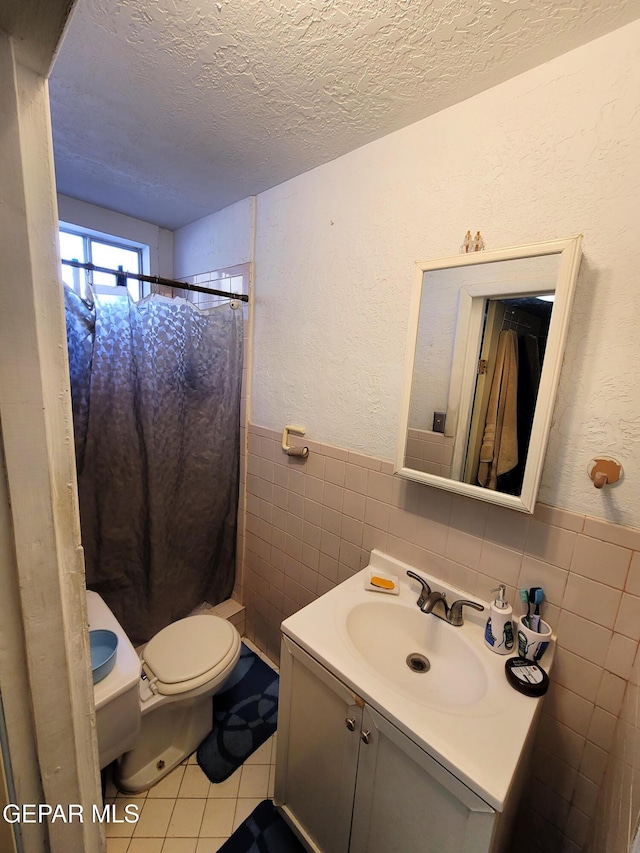 bathroom featuring tile patterned flooring, toilet, tile walls, and a textured ceiling