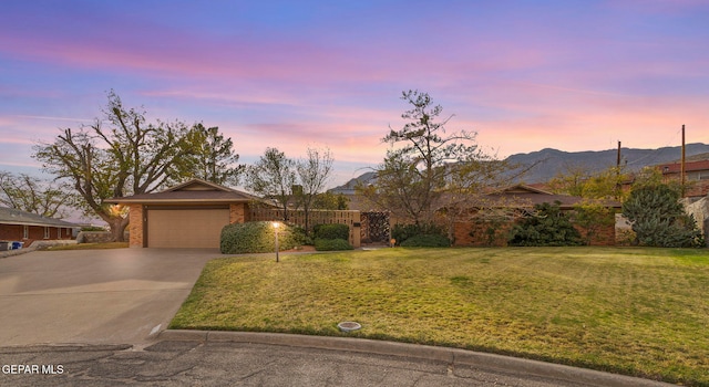 single story home with a garage, a mountain view, and a yard