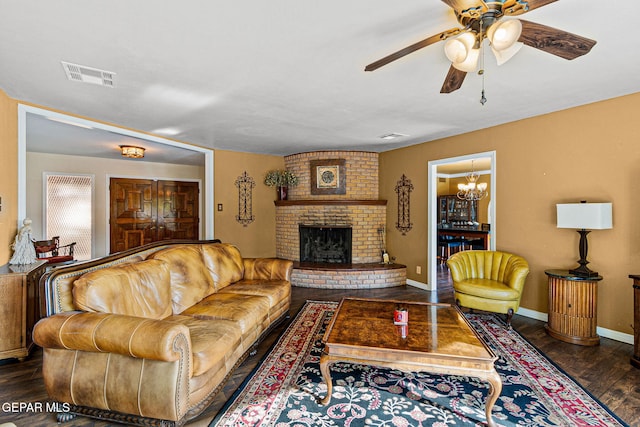 living room featuring dark hardwood / wood-style floors, ceiling fan with notable chandelier, and a fireplace