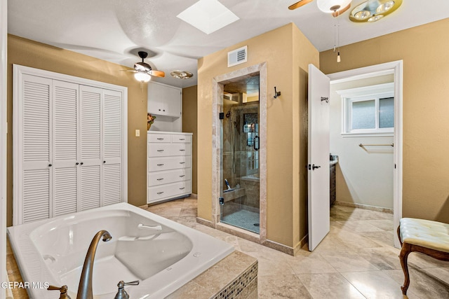 bathroom featuring plus walk in shower, ceiling fan, and a skylight