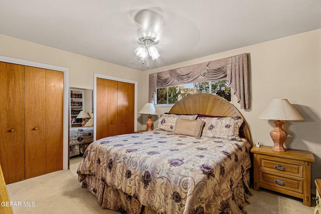 bedroom featuring light carpet, ceiling fan, and multiple closets