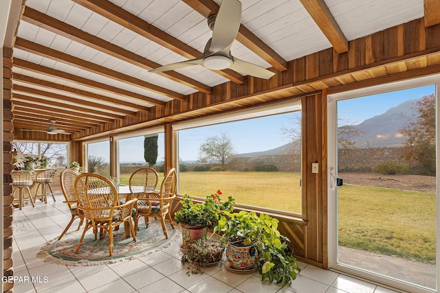 sunroom with beam ceiling, a mountain view, plenty of natural light, and ceiling fan