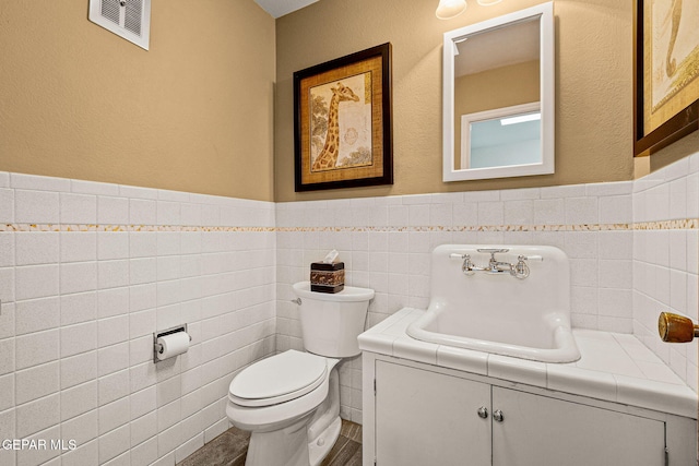 bathroom featuring sink, tile walls, and toilet