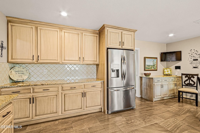 kitchen featuring light stone countertops, decorative backsplash, light brown cabinetry, and stainless steel fridge with ice dispenser