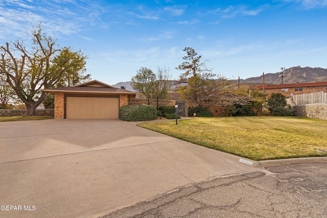 ranch-style house featuring a garage, a mountain view, and a front lawn