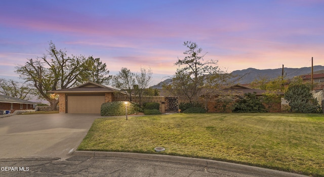 single story home featuring a garage, a mountain view, and a yard