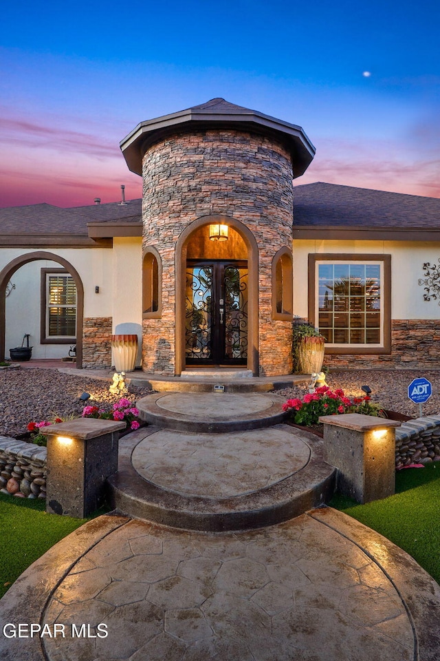 11179 Leo Collins Dr, El Paso, TX 79936 - exterior entry at dusk with stone siding, stucco siding, and french doors