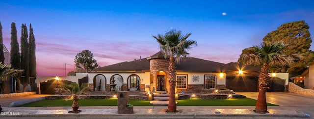 mediterranean / spanish home with an attached garage, a fire pit, stucco siding, a front yard, and driveway