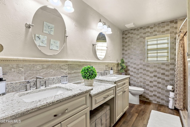 11179 Leo Collins Dr, El Paso, TX 79936 - bathroom featuring tile walls, two vanities, wood finished floors, and a shower with shower curtain