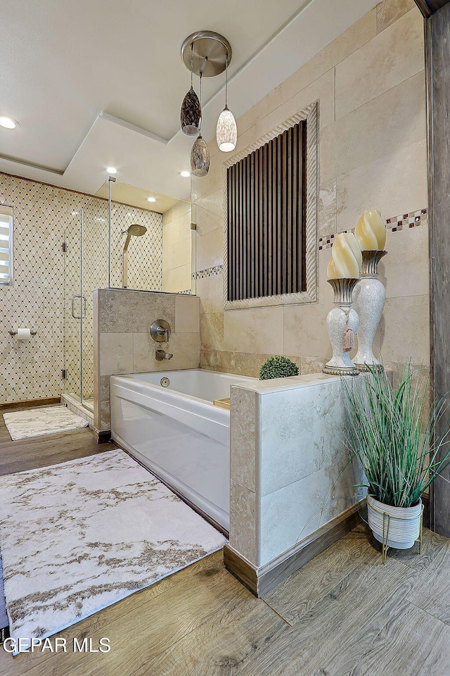 11179 Leo Collins Dr, El Paso, TX 79936 - bathroom featuring tile walls, a garden tub, a stall shower, and wood finished floors
