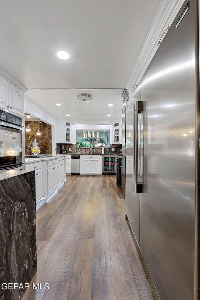 11179 Leo Collins Dr, El Paso, TX 79936 - kitchen featuring stainless steel appliances, white cabinets, wine cooler, wood finished floors, and recessed lighting