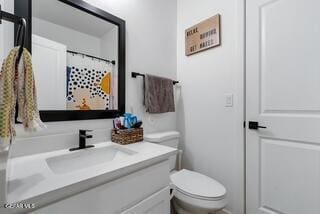 bathroom featuring vanity, curtained shower, and toilet