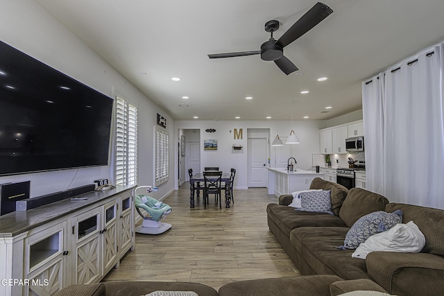 living room with ceiling fan and light wood-type flooring