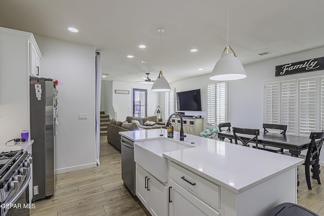 kitchen with appliances with stainless steel finishes, sink, a center island with sink, and white cabinets