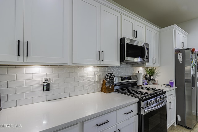 kitchen with decorative backsplash, white cabinets, and appliances with stainless steel finishes