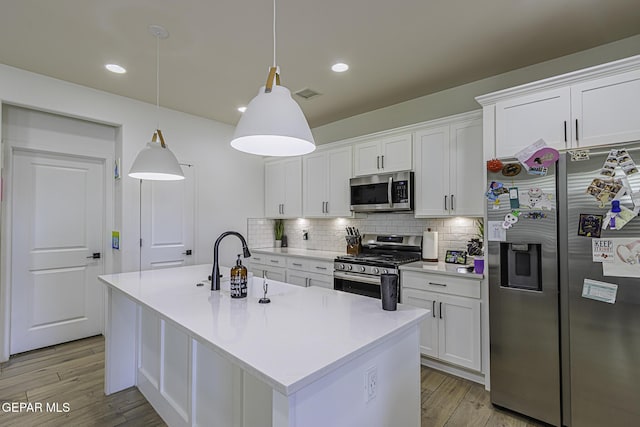 kitchen with decorative light fixtures, stainless steel appliances, and white cabinets